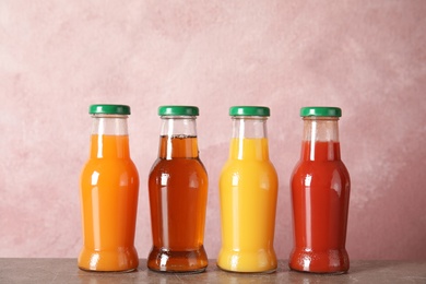 Bottles with different drinks on table against color background