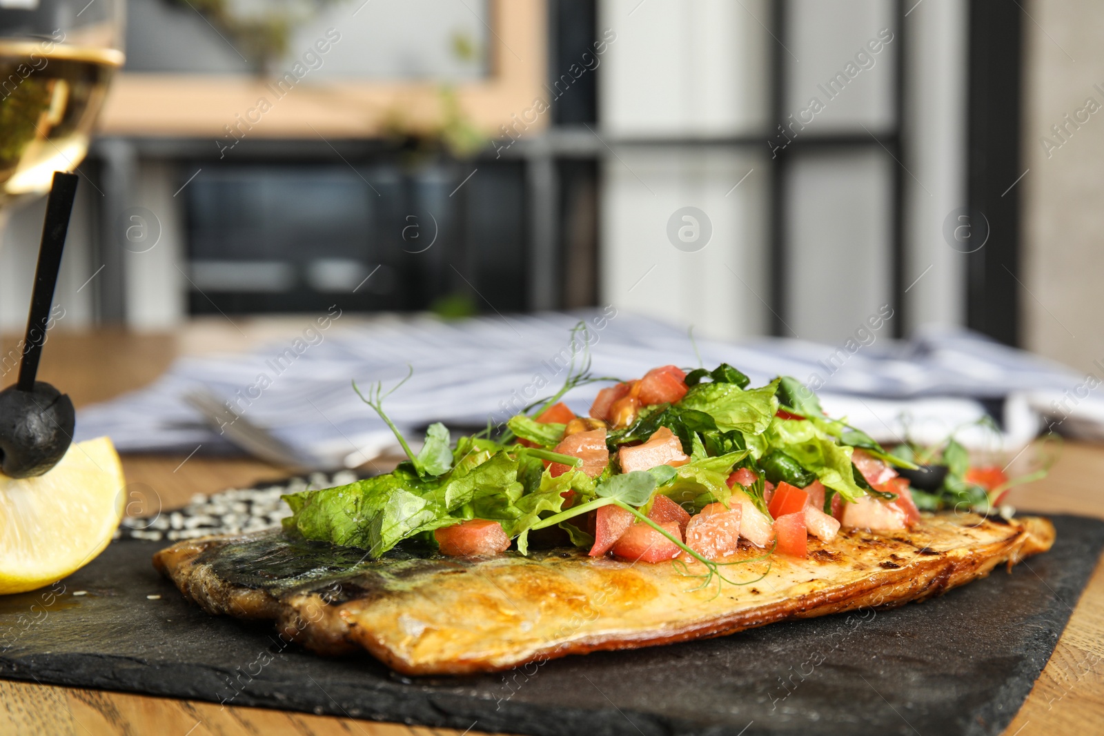 Photo of Delicious grilled fish with vegetables served on wooden table indoors