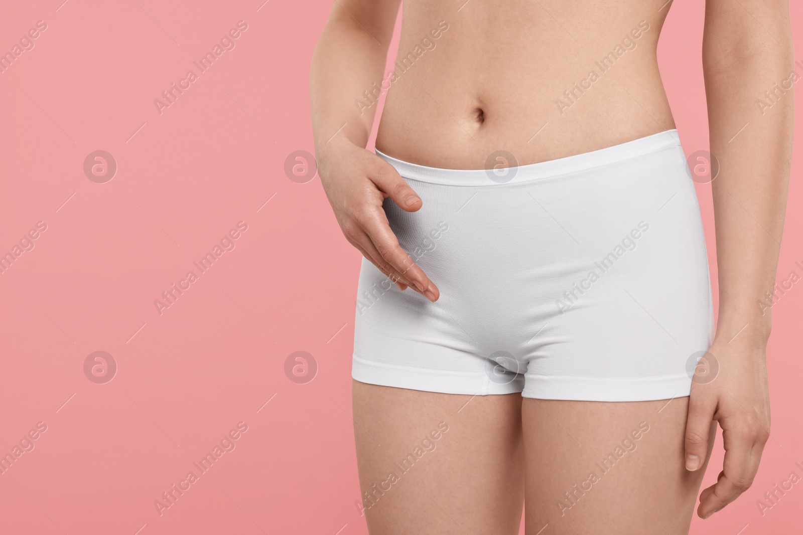 Photo of Woman holding hand near panties on pink background, space for text. Women's health