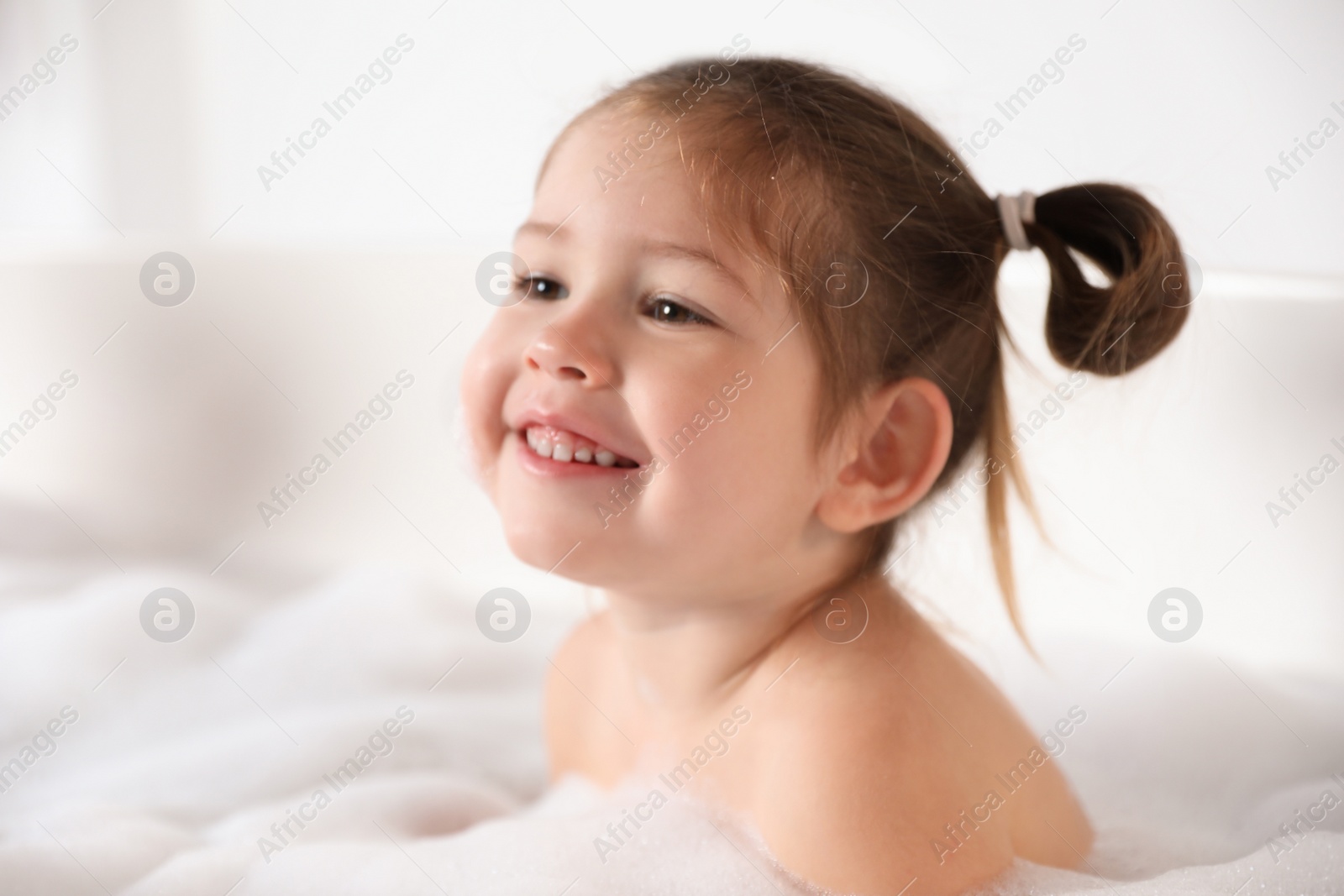 Photo of Cute little girl taking bubble bath at home