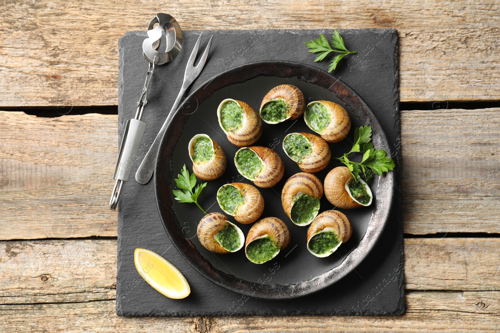 Photo of Delicious cooked snails served on wooden table, flat lay