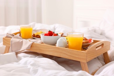 Photo of Good morning. Tray with tasty breakfast on bed at home