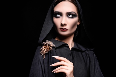 Photo of Mysterious witch with spooky spider on black background