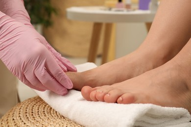 Professional pedicurist massaging client`s foot in beauty salon, closeup