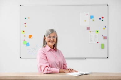 Photo of Portrait of professor sitting at desk in classroom