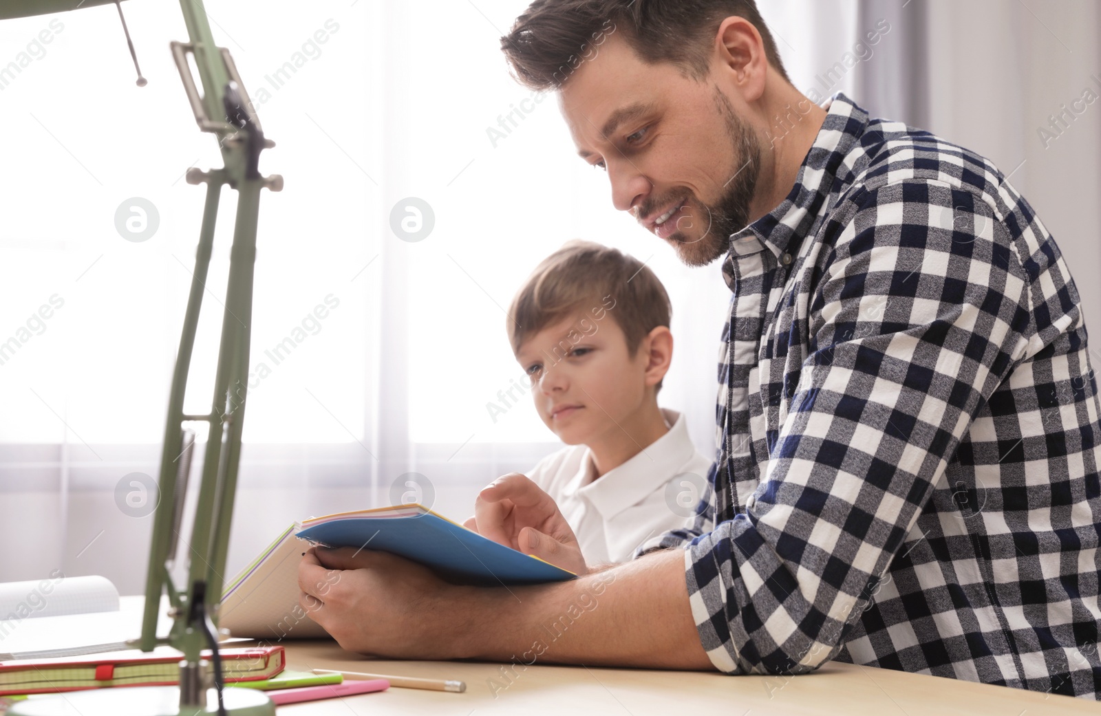 Photo of Dad helping his son with school assignment at home