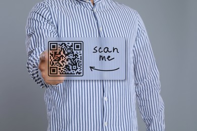 Image of Man pointing at illustration of QR code on light grey background, closeup
