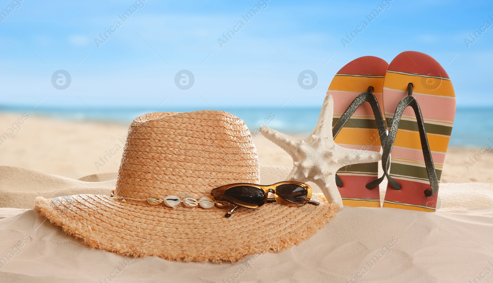 Image of Different beach accessories on sand near ocean