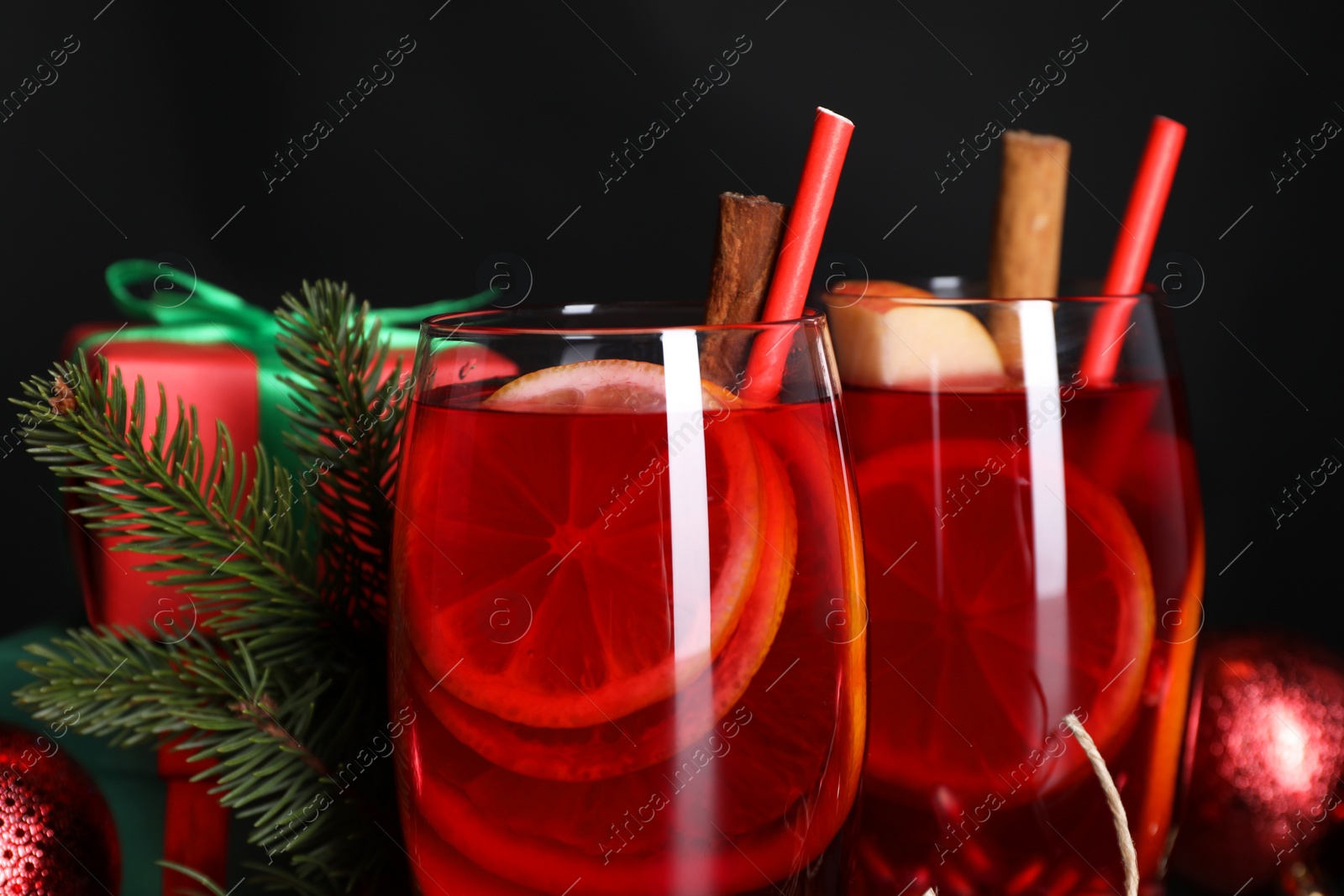 Photo of Delicious Sangria drink in glasses and Christmas decorations on black background, closeup