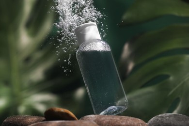 Photo of Bottle of micellar water in liquid on blurred background