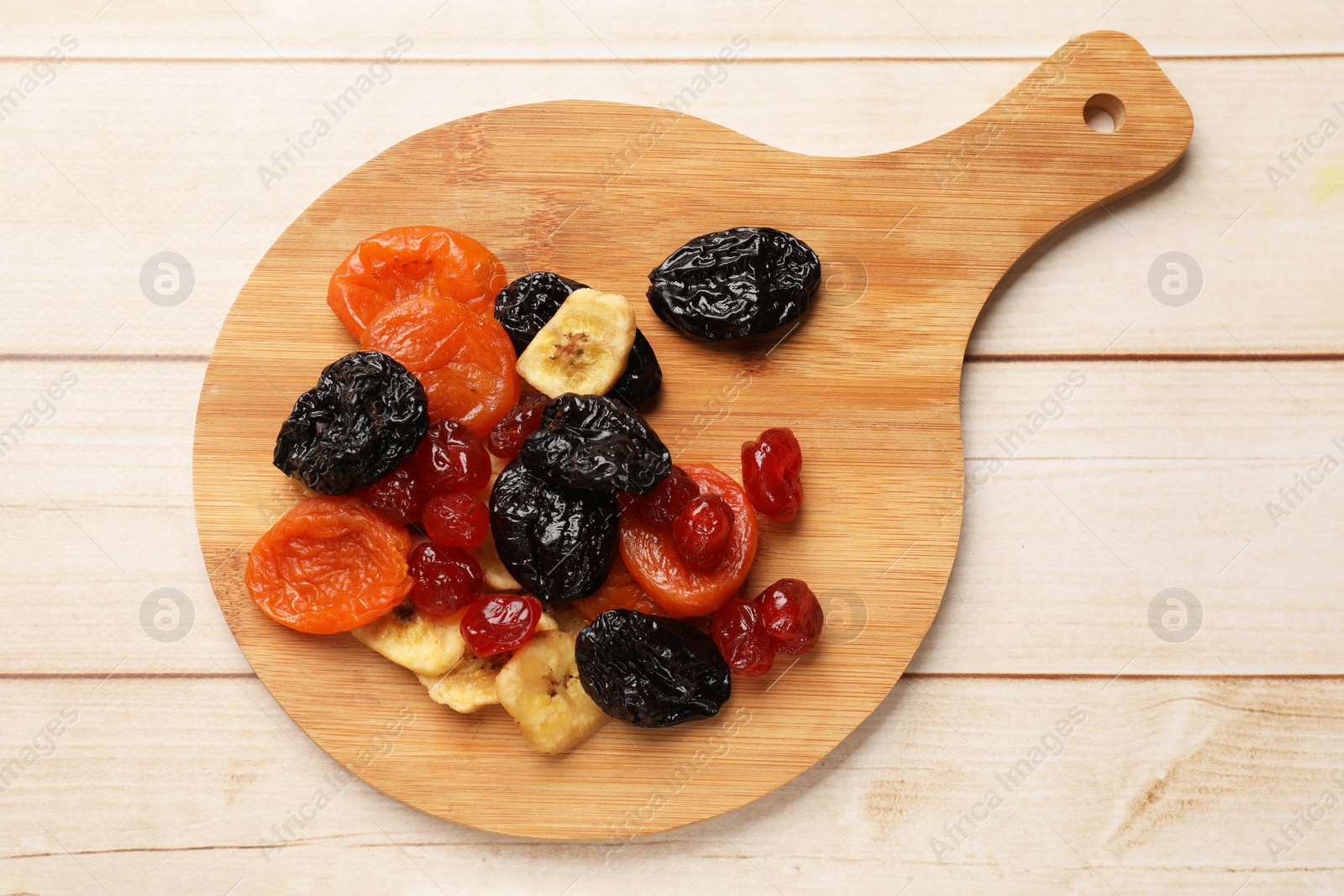 Photo of Mix of delicious dried fruits on white wooden table, top view