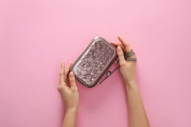 Woman holding stylish handbag on pink background, closeup