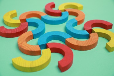 Photo of Colorful wooden pieces of play set on green background, closeup. Educational toy for motor skills development