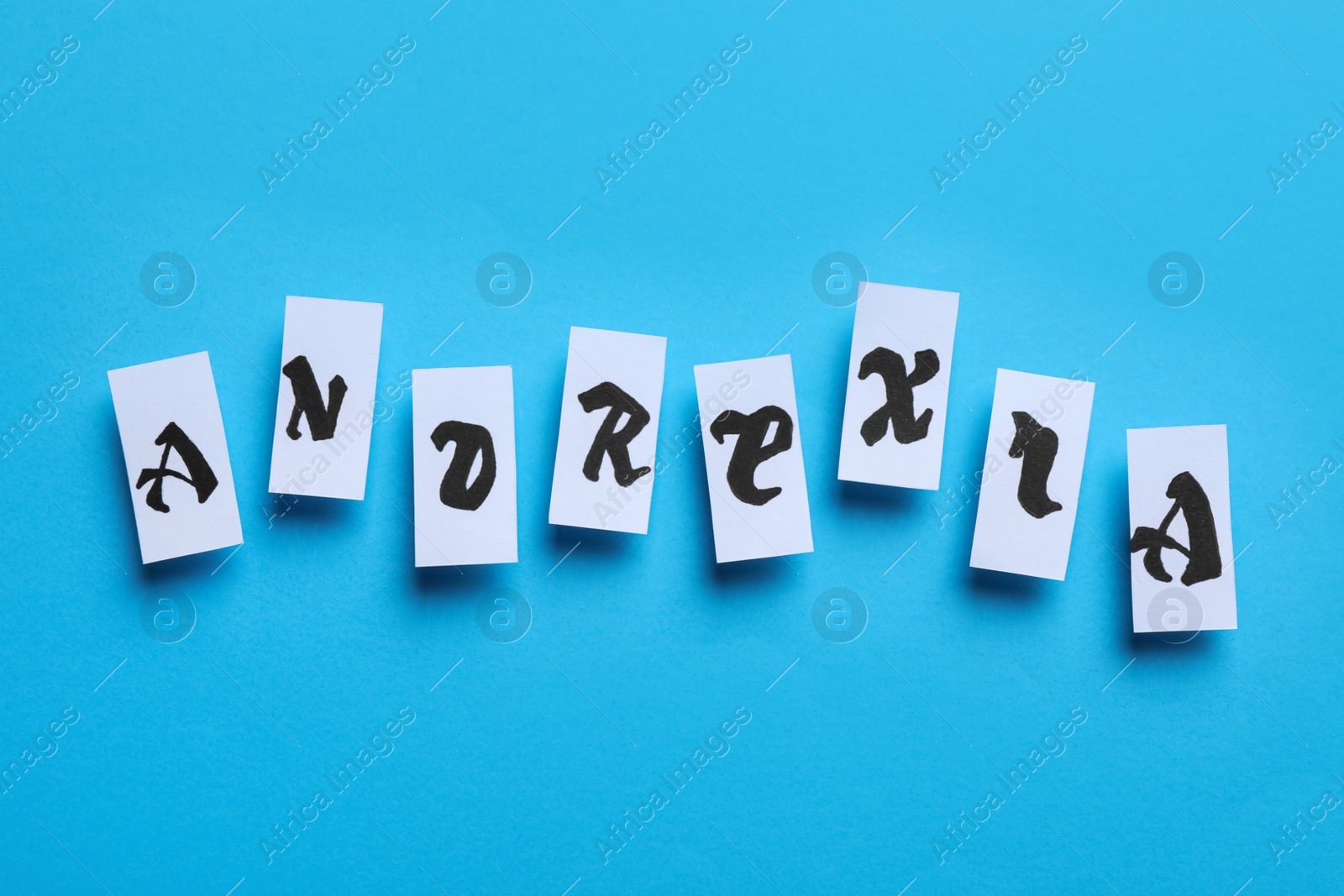 Photo of Word Anorexia made of paper pieces with letters on light blue background, flat lay