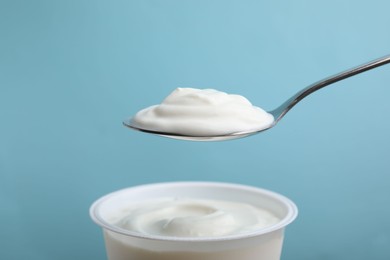 Photo of Eating delicious natural yogurt on light blue background