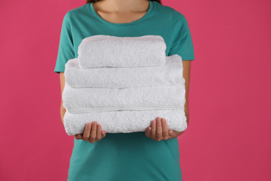 Photo of Woman holding fresh towels on pink background, closeup