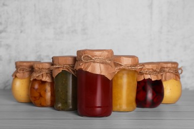 Photo of Jars with canned fruit jams on wooden table