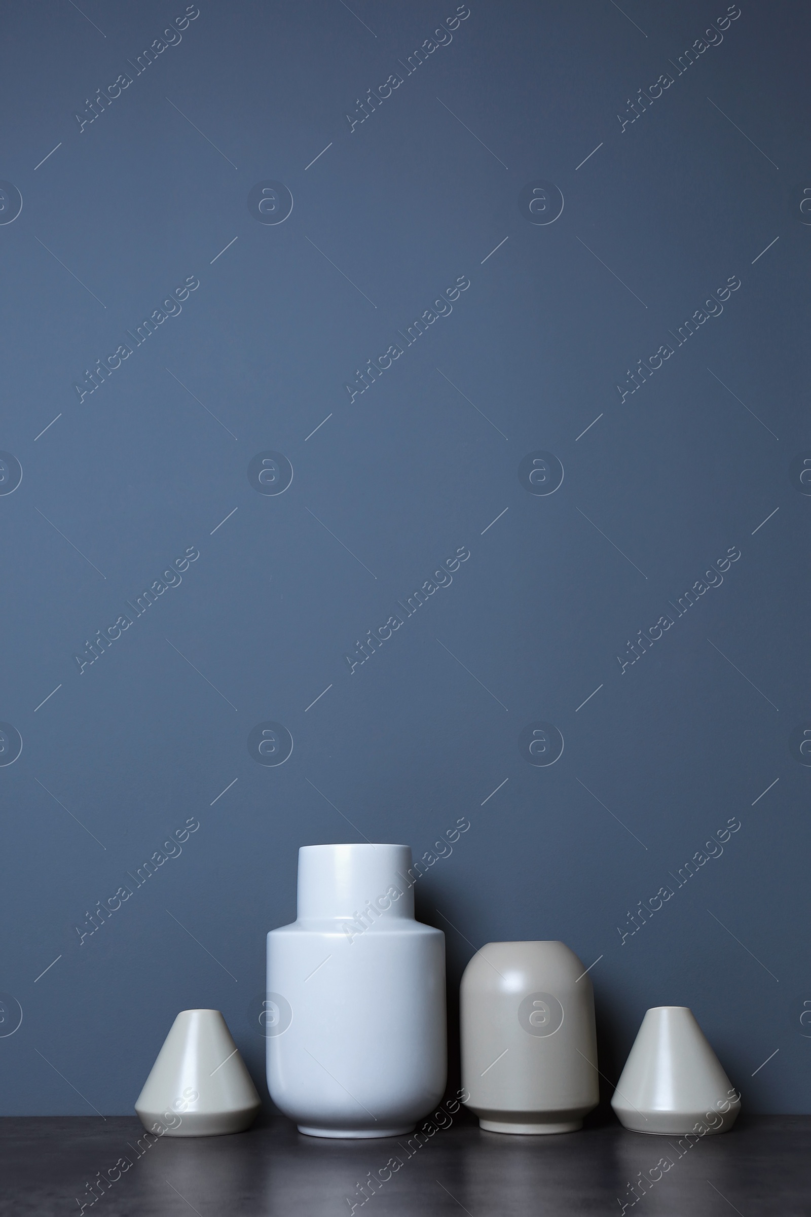 Photo of Beautiful ceramic vases on table against color wall