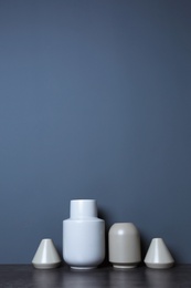 Photo of Beautiful ceramic vases on table against color wall