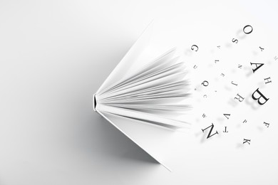 Image of Open book with letters flying out of it on white background, top view