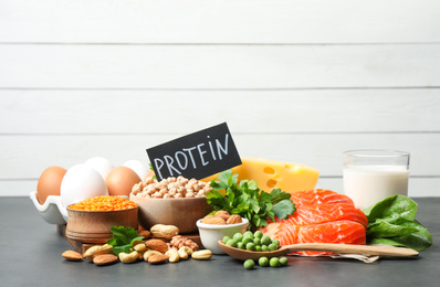 Photo of Card with word PROTEIN and different products on black table