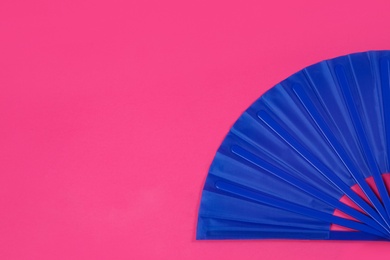 Blue hand fan on pink background, top view. Space for text