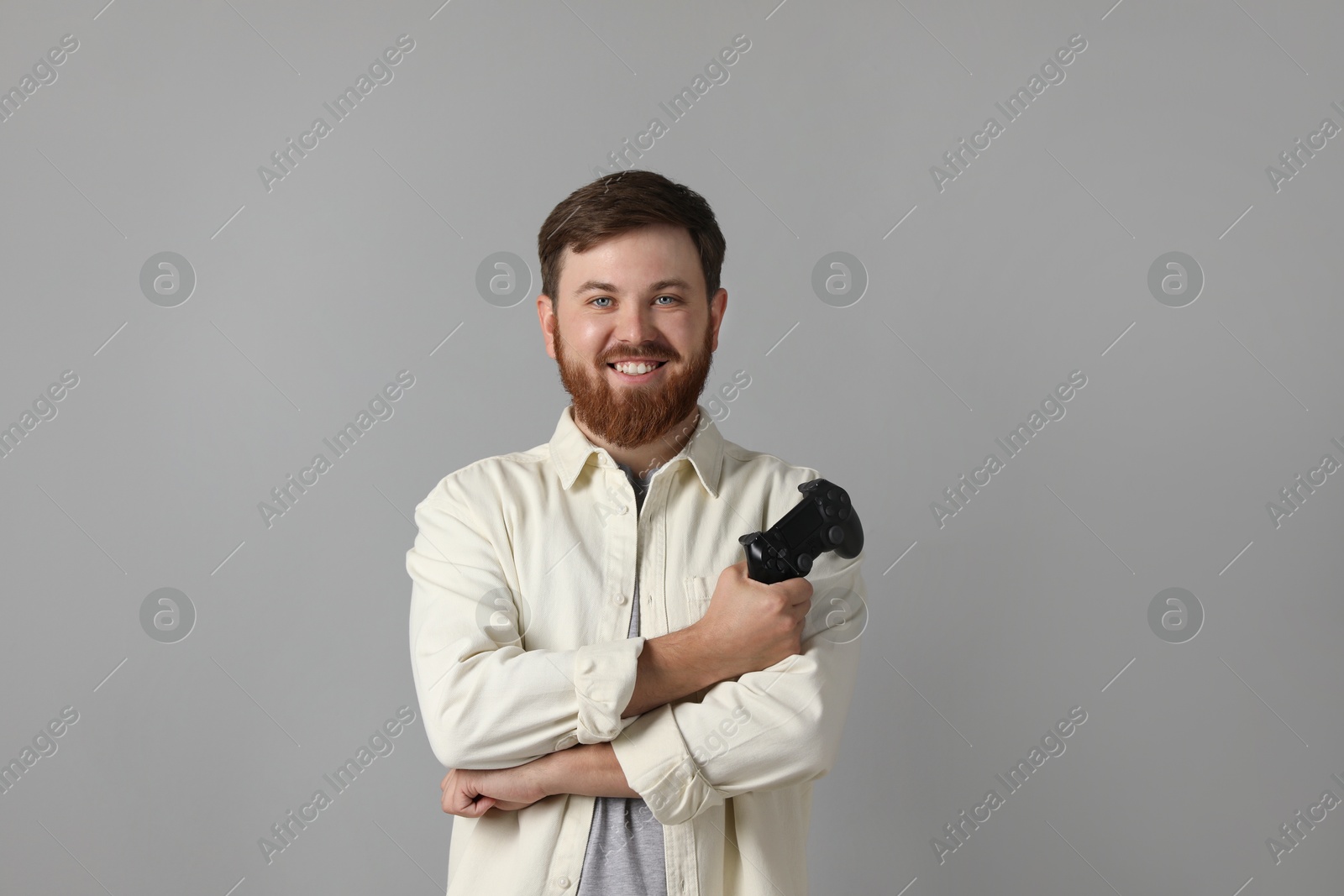 Photo of Smiling man with game controller on grey background