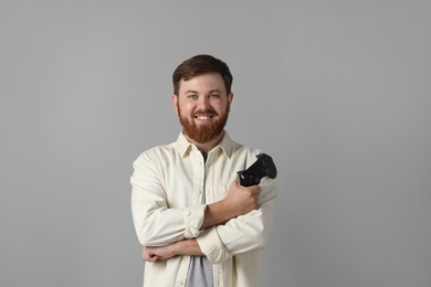 Smiling man with game controller on grey background