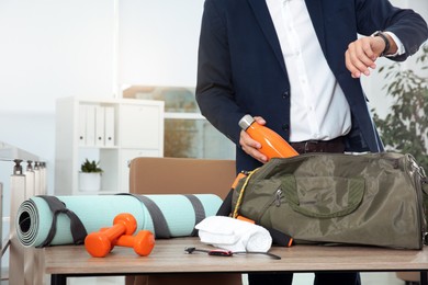 Photo of Businessman packing sports stuff for training into bag in office, closeup