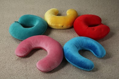 Photo of Many colorful travel pillows on beige rug