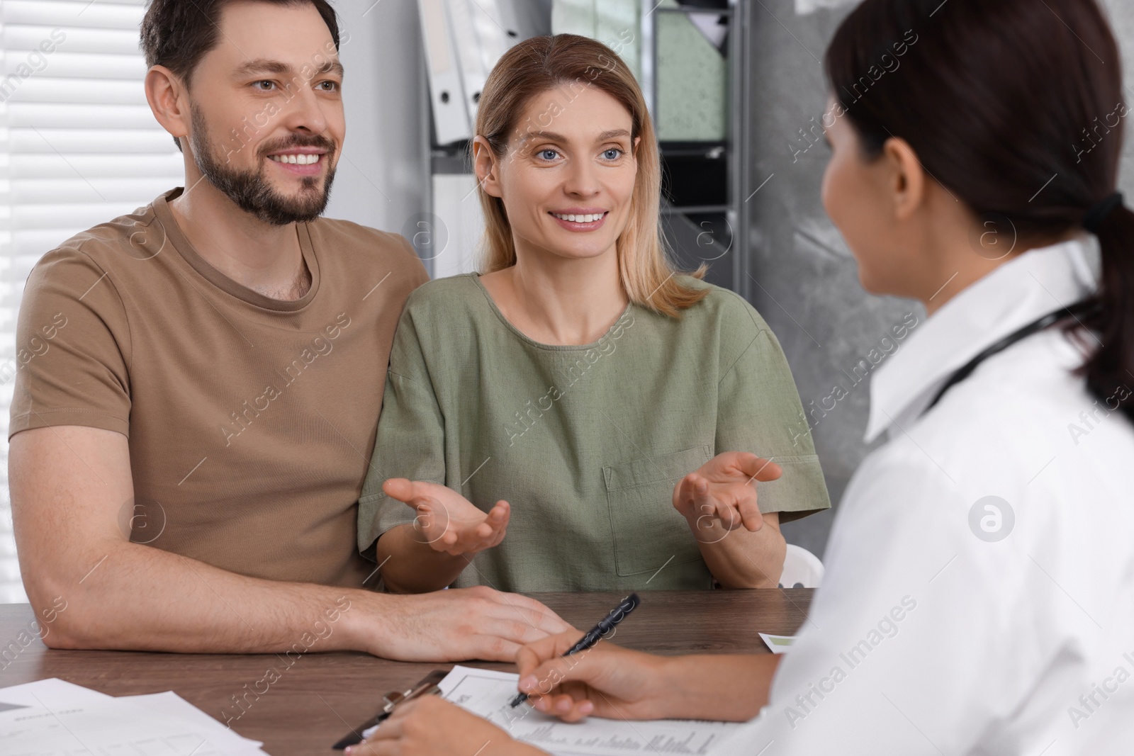 Photo of Couple having appointment with fertility doctor in clinic. Patient consultation