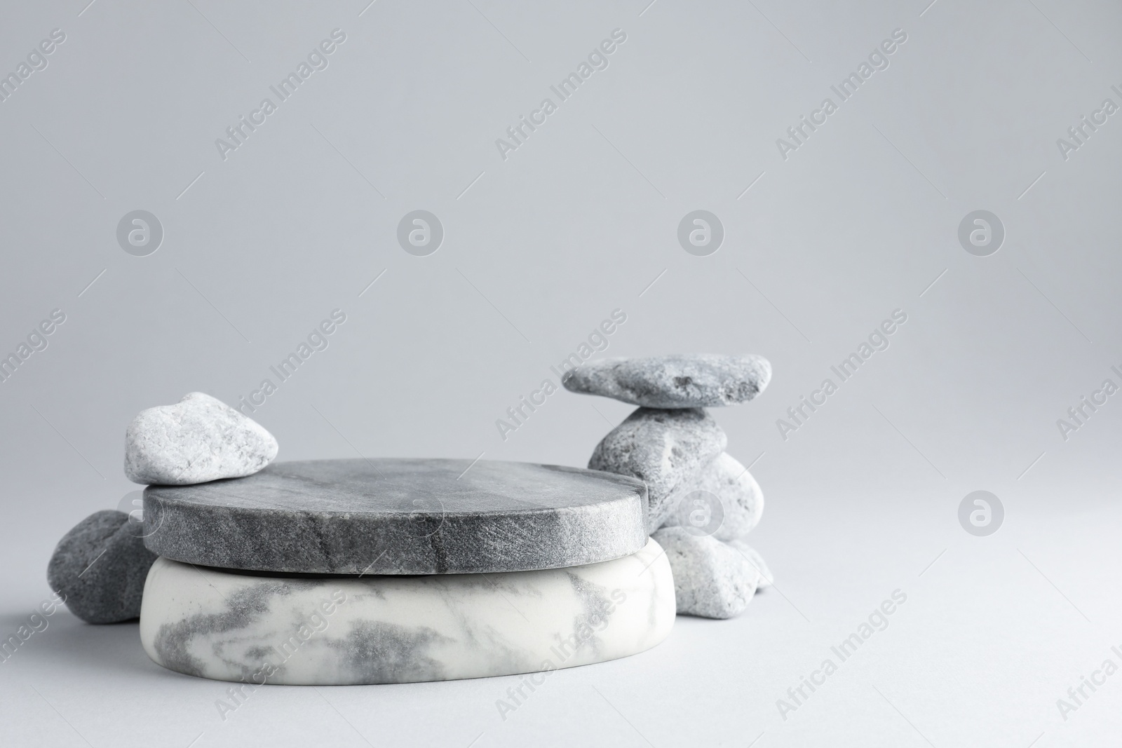 Photo of Presentation for product. Stone podium and pebbles on light grey background. Space for text