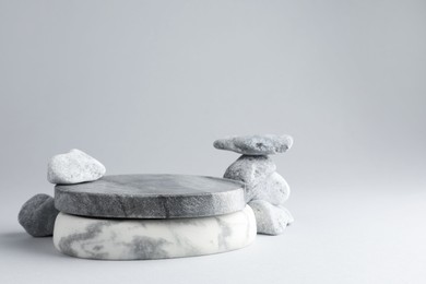 Photo of Presentation for product. Stone podium and pebbles on light grey background. Space for text