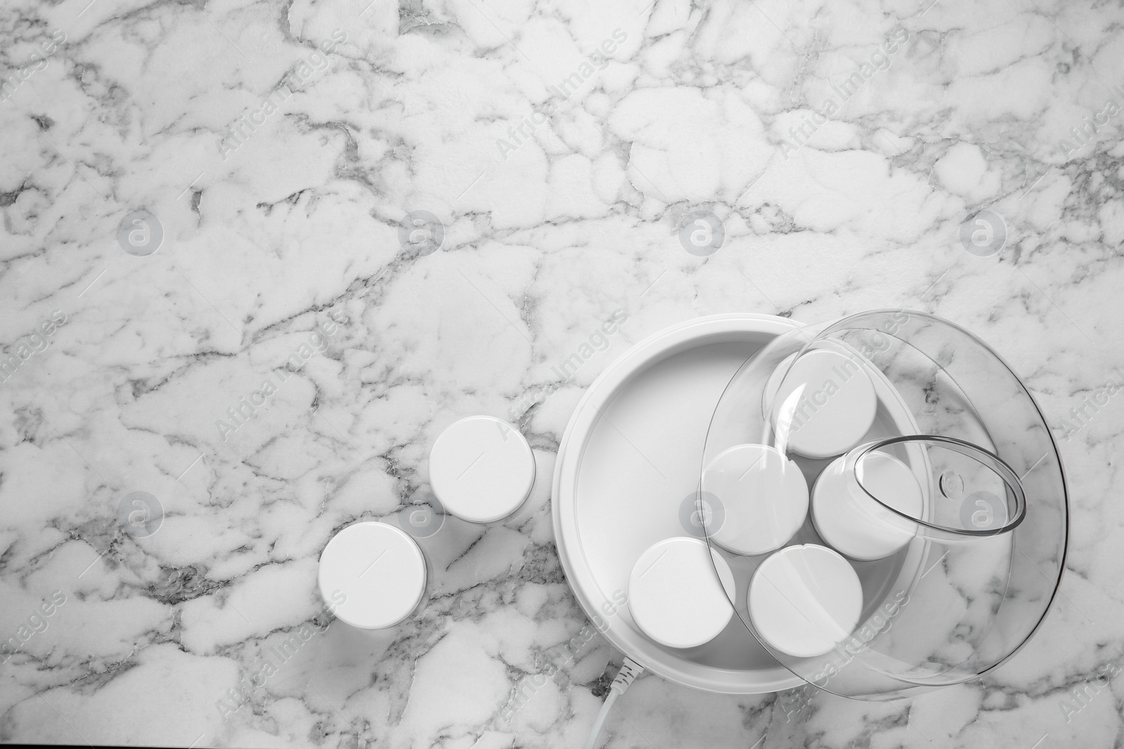 Photo of Modern yogurt maker with jars on white marble table, flat lay. Space for text