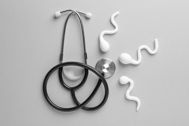 Photo of Reproductive medicine. Figures of sperm cells and stethoscope on gray background, flat lay