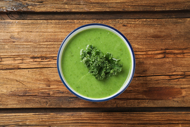 Photo of Tasty kale soup on wooden table, top view