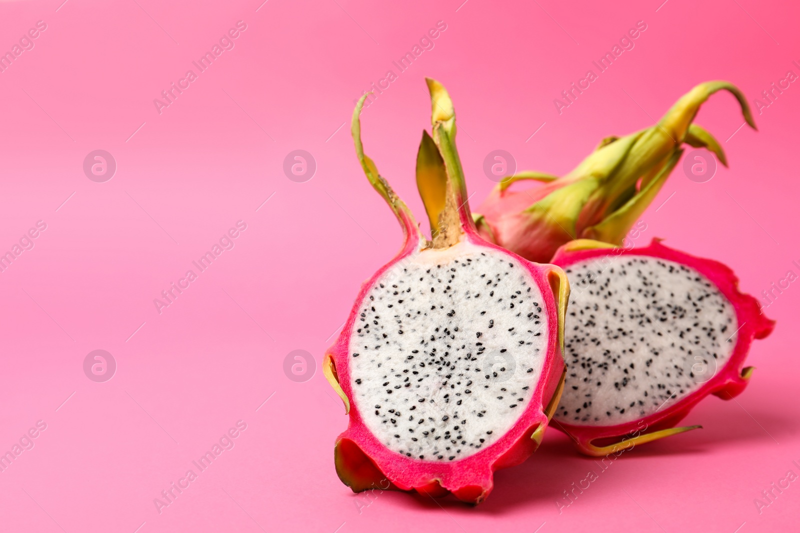 Photo of Delicious cut and whole dragon fruits (pitahaya) on pink background