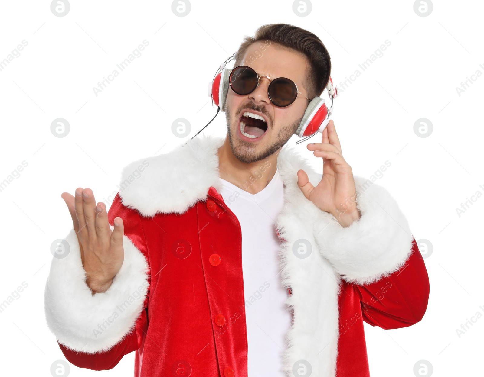 Photo of Young man in Santa costume listening to Christmas music on white background