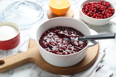 Photo of Fresh cranberry sauce in bowl served on white marble table, closeup