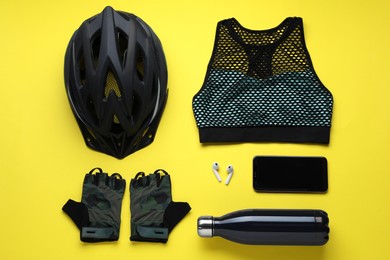 Photo of Flat lay composition with different cycling accessories and clothes on yellow background