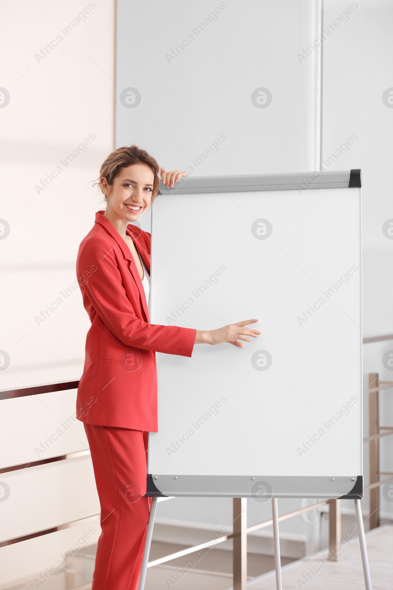 Photo of Female business trainer giving presentation on whiteboard indoors