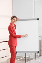 Female business trainer giving presentation on whiteboard indoors