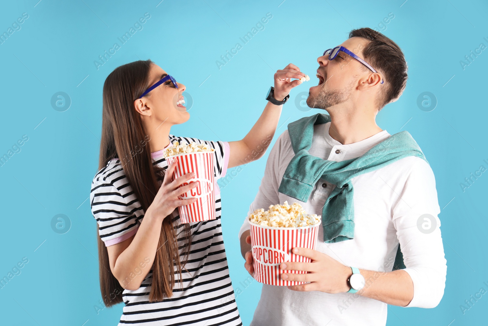 Photo of Couple with 3D glasses and tasty popcorn on color background