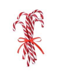Photo of Sweet Christmas candy canes with red bow on white background, top view