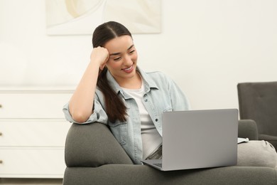 Woman using laptop on couch at home