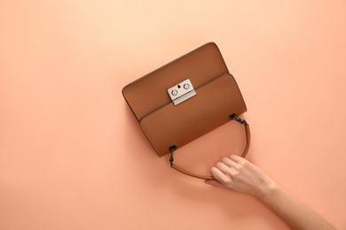 Woman holding stylish handbag on beige background, closeup