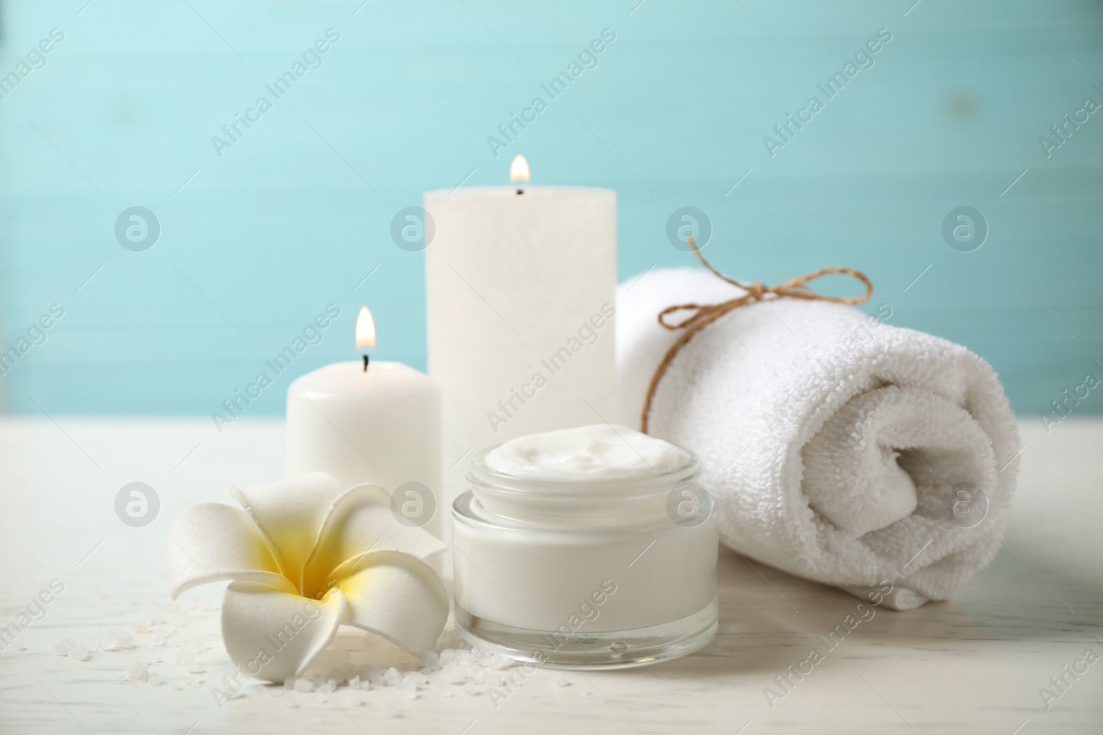 Photo of Composition with cream and burning candles on white wooden table. Spa treatment