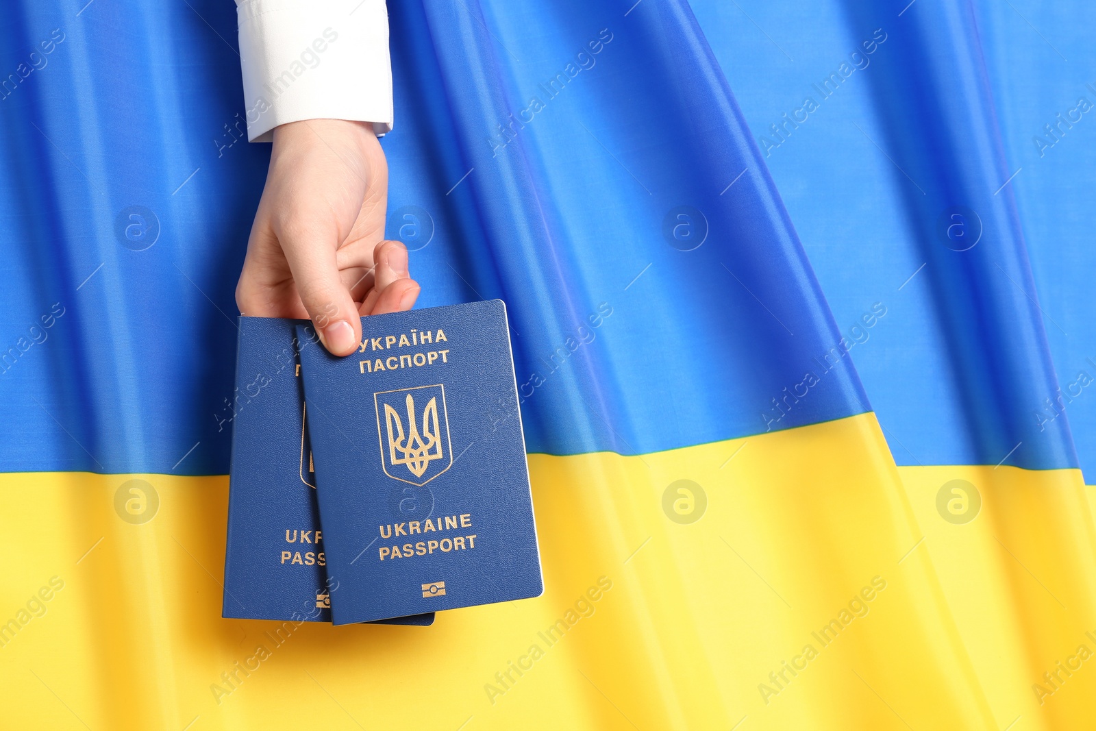 Photo of Woman holding Ukrainian travel passports over national flag, top view with space for text. International relationships