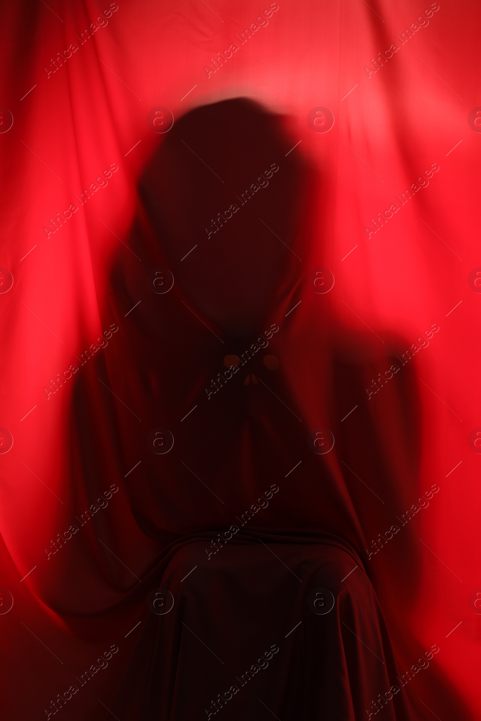 Photo of Silhouette of creepy ghost behind red cloth