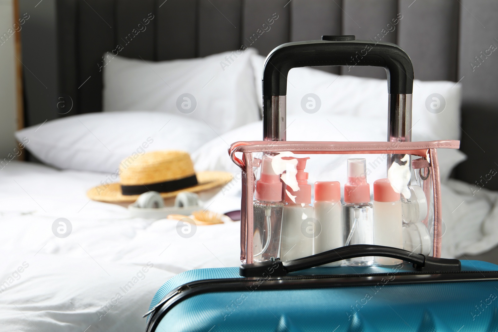 Photo of Cosmetic travel kit. Plastic bag with small containers of personal care products on suitcase in bedroom, space for text